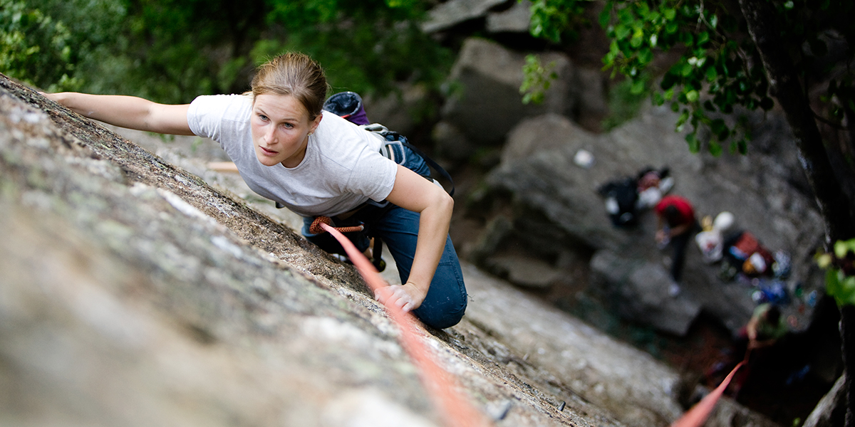 woman scaling a steep rock wall