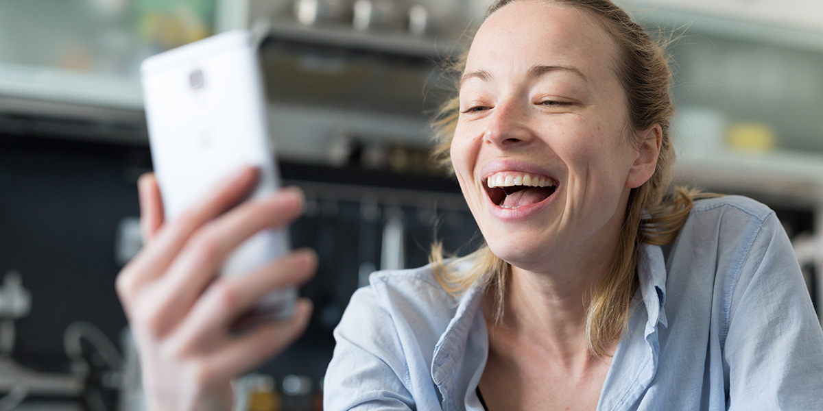 woman laughing as she looks at her phone